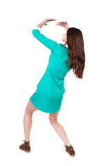 back view woman in a dress protects hands from what is falling from above. Rear view people collection.  backside view of person.  Isolated over white background.  The girl in a green dress simply