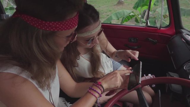Hippie Girls Use Smartphone Sitting in a Car Cabine. Slow Motion