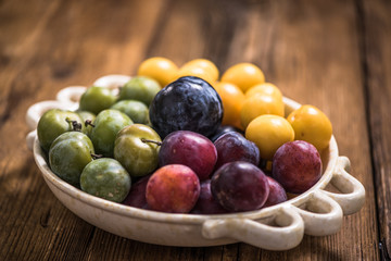 varieties of plums in rustic bowl