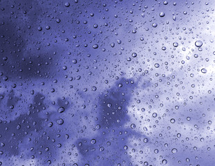 Drops of rain on glass , rain drops on clear window / rain drops with clouds / water drops on glass after rain background / water drops / Small water drops on the glass.