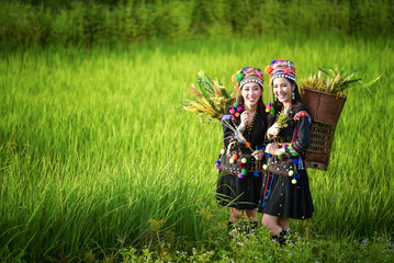 Two women wearing tribal costumes work in the fields of rice terraces .