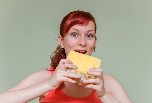 young beautiful girl bites cheddar cheese on green background