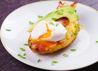 Stuffed potato with bacon, poached egg, avocado, cheese and spring onion