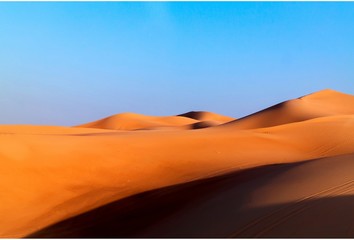 Arabian desert dune background on blue sky. Desert near the city of Dubai. large red and yellow dune illuminated by bright sunlight