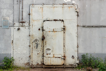 Closed old white metal door in an industrial building