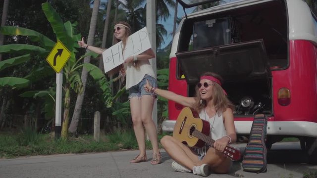 Hippie Girls with a White Panel in Hands Catch Passing Car near the Broken Minivan. Slow Motion