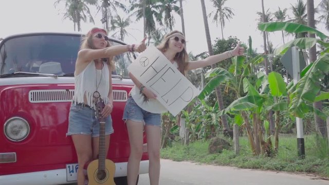 Hippie Girls with a White Panel in Hands Catch Passing Car near the Broken Minivan. Slow Motion