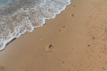 Detail of footprints on the sand and sea