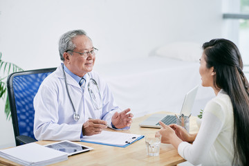 Obraz premium Vietnamese doctor consulting female patient in his office