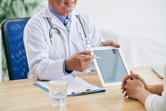 Cropped image of doctor showing information on tablet to patient