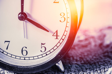 closeup vintage clock selective focus at number 4 o'clock with sun light vintage color tone for postcard.