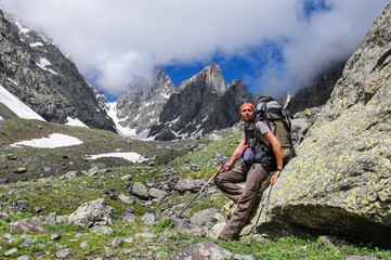 Young tourist with big backpack going up in the mountains