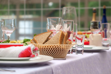 Basket of sliced bread served with dishes on the table for the holiday. Cutlery and food on white tablecloths in the restaurant. Design a festive Banquet. Luxurious food for guests and visitors.