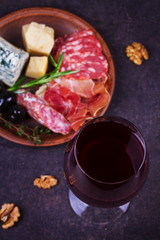 Red wine with blue cheese, parmesan, salami, prosciutto, olives, rosemary and bread. View from above, top studio shot