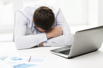 businessman with laptop and papers in office