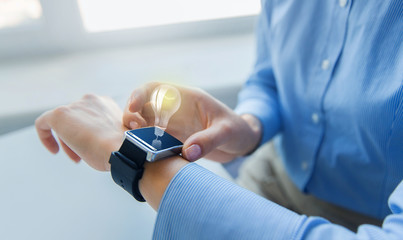 close up of hands with smart watch and light bulb