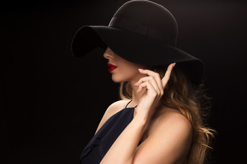 beautiful woman in black hat over dark background