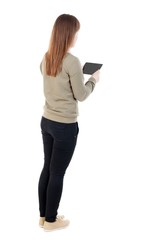 back view of standing young beautiful  girl with tablet computer in the hands of. girl  watching. Rear view people collection.  backside view of person.  Isolated over white background.