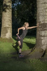 Fototapeten sportieve jonge vrouw doet buiten in het park sport oefeningen © monicaclick