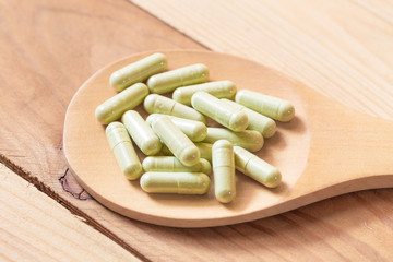 Fototapeta na wymiar green herbal powder in capsule on wood background, Dried Kariyat for medicine.