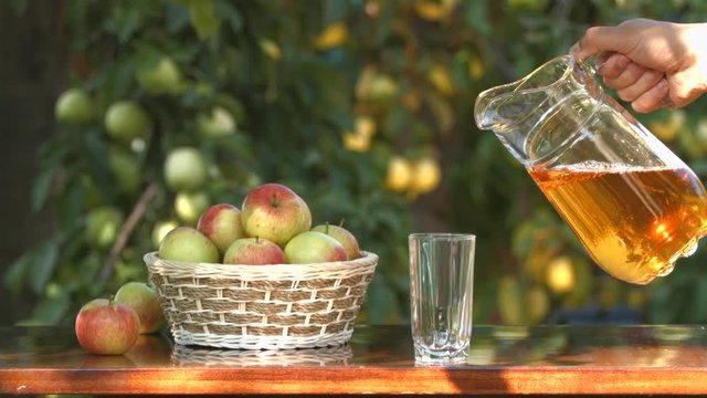 Apple juice on the background of growing apples. 2 Shots. Slow motion. Focus in \ focus out.