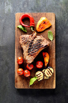 grilled beef steak on a cutting board on a black background