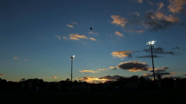 Shilouetted football players practicing in a stadium.