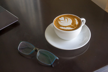 Laptop , cup of coffee and eyeglasses on table