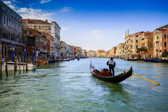 Gondolier sailing a gondola and view of the Grand Canal, Venice, Italy