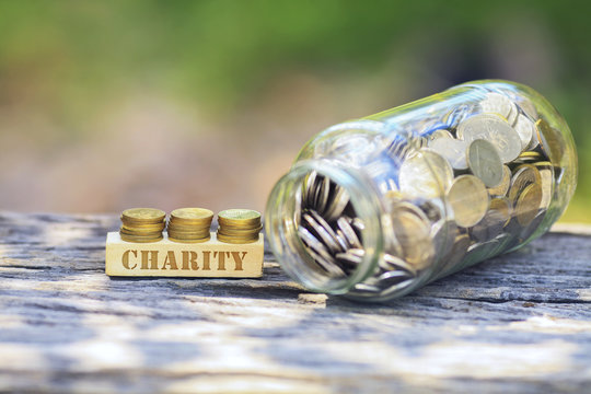Business Concept - CHARITY WORD Golden coin stacked with wooden background