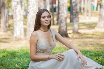 Fototapeta premium Beautiful girl in dress sitting on the grass