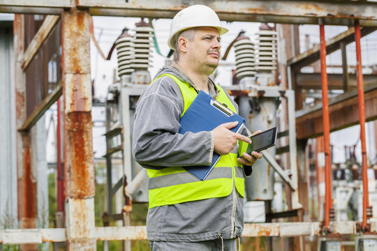 Electrician using tablet PC in electrical substation