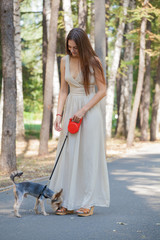 A girl in a long dress on a walk with a Yorkshire Terrier