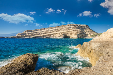 Matala beach on Crete island, Greece. Tourists relax and bath in crystal clear water of Matala in south of Creta. There are many caves near the beach.