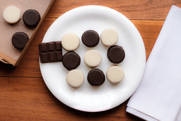 Obraz na płótnie Canvas Black and white chocolate alfajores on white plate with cloth na