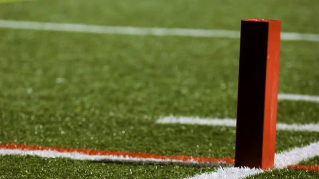 Rack focus to an end zone pylon on a football field.
