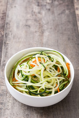 Carrot and zucchini noodles on wooden table

