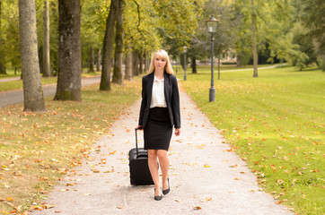 Fototapeta premium Elegant professional woman pulling her luggage