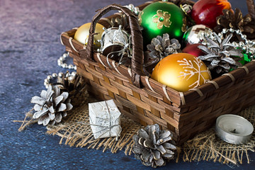  Preparation for Christmas. Basket with ornaments for a Christmas tree, candle and pine cones on a blue background.