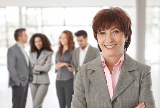 Middle-aged businesswoman in front of colleagues