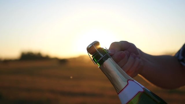 a guy opens a bottle of champagne