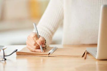 Close-up image of woman taking notes when working