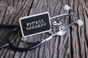 Medicine concept. Blackboard with word BYPASS SURGERY  and stethoscope on wooden background