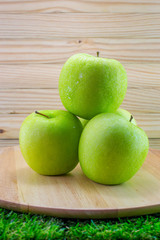 Green apples with water drop on wooden tray and wooden background
