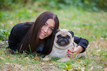 girl and her best friend, pug lying on the grass