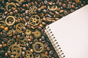 mock up for background in steampunk style. Roasted coffee beans mixed with brass gears and empty notepad with blank for text. Grunge style toned. Top view.