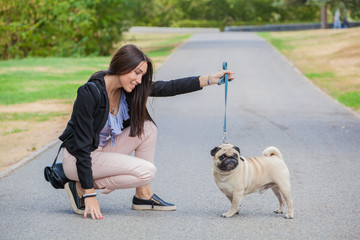 Sport girl and pug on a leash walk in the park