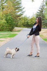 Sport girl and pug on a leash walk in the park