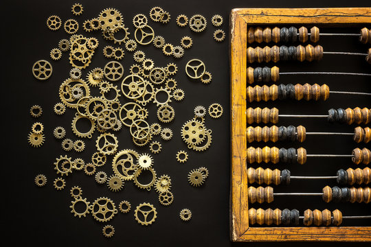 Old wooden scratched vintage decimal abacus and steampunk gears on a black desktop from chalkboard with blank for inscription for the background. Top view. Flat lay.