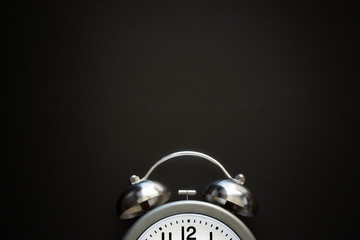 Classic alarm clock with bells and arrows on background from black chalkboard. Top view. Close up....